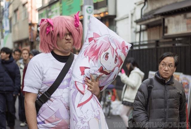 Hình ảnh một wibu truyện tranh ăn mặc giống và ôm cả gối có in hình nhân vật manga mình hâm mộ ra đường